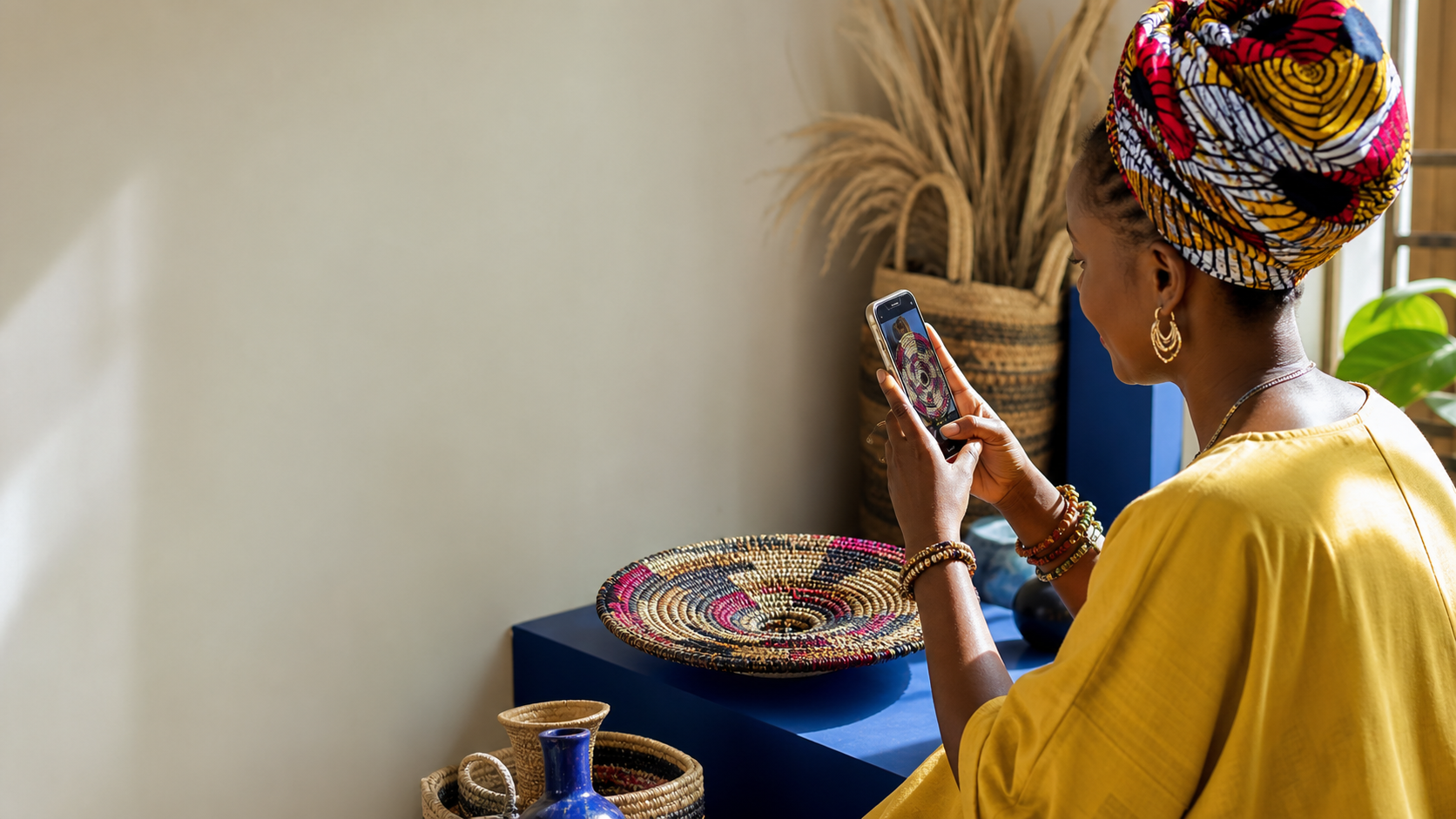 A homeware seller photographing a handmade product with a smartphone in a sunlit studio.
