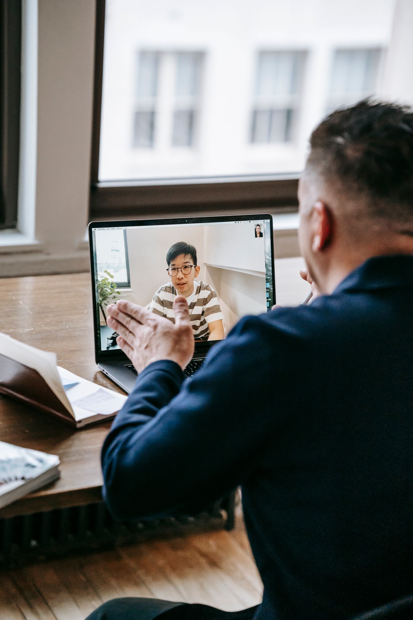 A professional speaking with a colleague through a laptop video call.