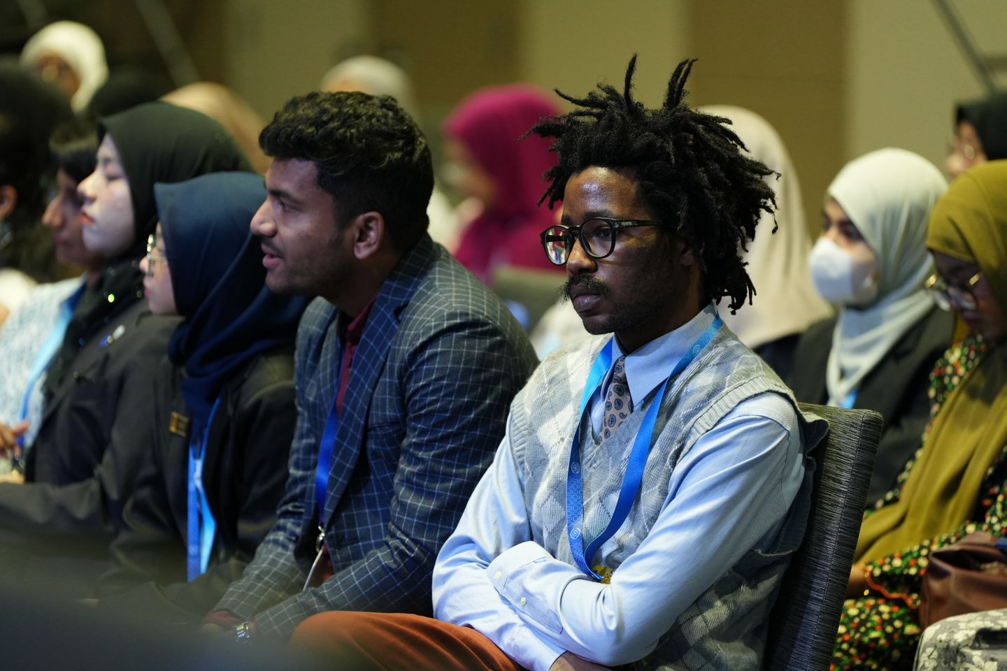 An audience listening to a speaker at an indoor conference.