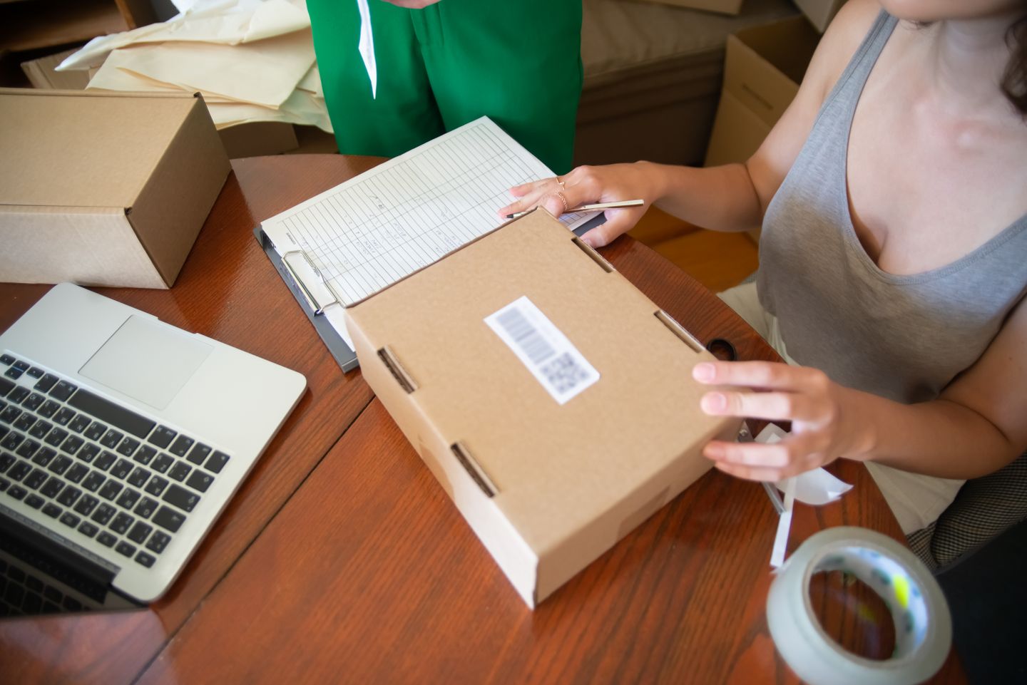Two people packing customer orders at a worktable with a laptop.